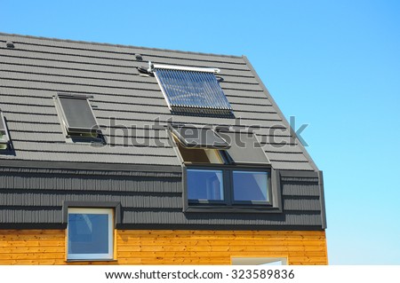 Closeup of Solar Water Panel Heating, Dormers, Solar Panels, Skylights, Ventilation and Air Conditioning Systems Installed on House Roof. Energy Efficiency New Passive House Building Concept.