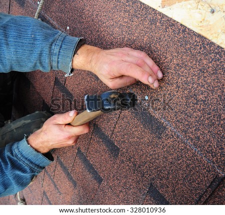 Roofer Install Bitumen Roof  Asphalt Shingles with Hammer - Closeup on Hands. Roofing Repair