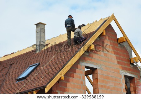 Roofing Construction and Building New Brick House with Modular Chimney, Skylights, Attic, Dormers and Eaves Exterior. Roofers Install, Repair Asphalt Shingles or Bitumen Tiles on the Rooftop Outdoor.