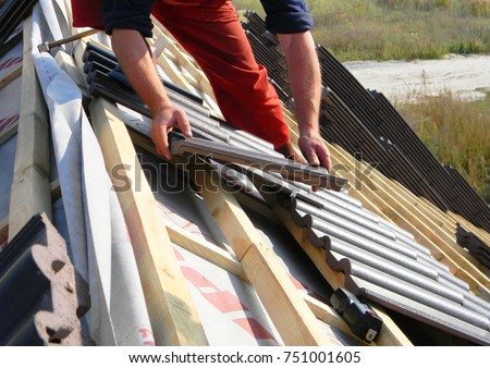 Roofing construction with clay roof tiles. Roofer laying ceramic roof tiles. Lay roof tiles.