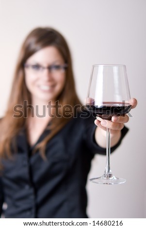 Modern young woman holding a wine glass with liquid in it doing a \