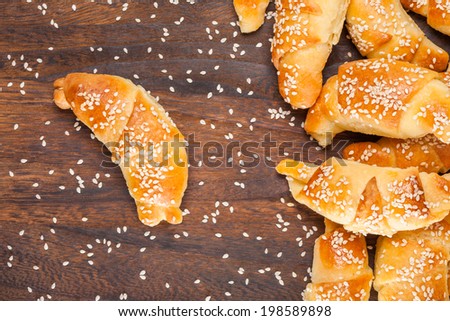 Mini croissants filled with cheese, with sesame on a wooden table