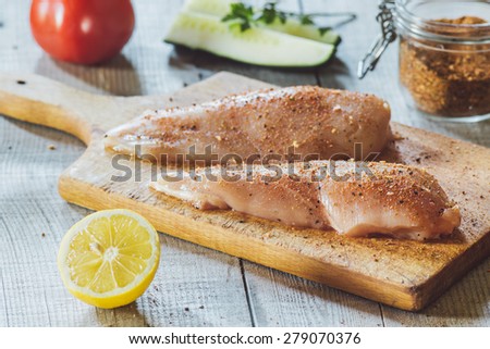 Fresh meat on wooden board with spice, tomato and lemon on table
