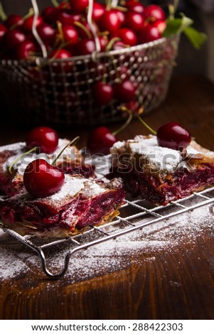 Homemade cherry pie covered in sugar with fresh cherries on top
