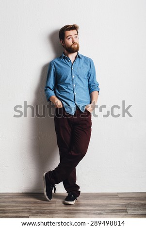 Young handsome man leaning against a white wall