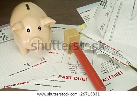 Pink piggy bank with toy hammer pictured against a background of past due bills and invoices.