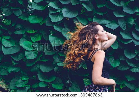 young woman, against background of summer green park, green leaves. Running girl with beautiful curly hair