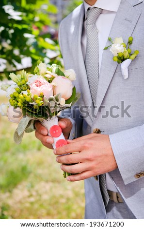 The groom in a gray suit with a wedding bouquet