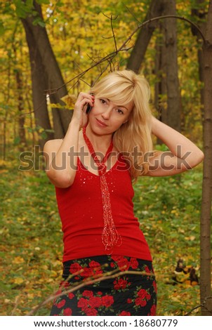A young blond woman with a  mobil in the autumn forest