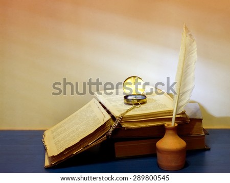 Still life of books, inkwells, pen and clock on vintage background and shadow on the blinds