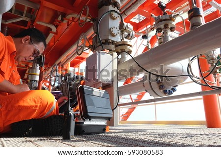 Mechanical technician hooked up to junction box of flow meter for check and inspect, performing various mechatronic checks, outputting the condition in a graph.