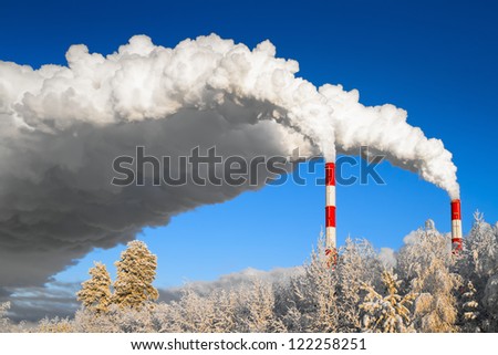 Smoking pipes of power station against the winter sky and the become covered with hoarfrost trees, Russia, Siberia, Surgut