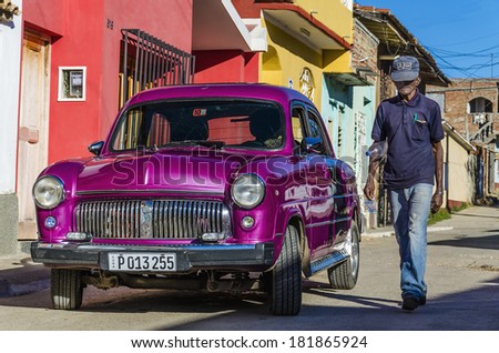 TRINIDAD, CUBA - DECEMBER 8, 2013: Typical view of purple classic American car on streets of Cuban small town, where old vehicles in perfect conditions are iconic for Cuban culture after Revolution