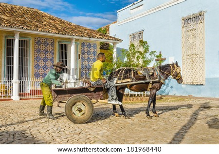 TRINIDAD, CUBA - DECEMBER 9, 2013: Typical Cuban workers loading horse carriage on streets of small colonial town Trinidad, where people still use horses and oxen for  transportation and field work