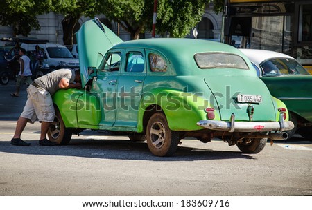 HAVANA, CUBA - DECEMBER 1, 2013: Cuban man repairing broken classic American car on streets of Havana, where old vehicles become relic part of Cuban cities after Fidel Castor revolution in 1960\'s