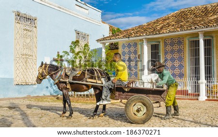 TRINIDAD, CUBA - DECEMBER 9, 2013: Typical Cuban workers loading horse carriage on streets of small colonial town Trinidad, where people still use horses and oxen for transportation and field work