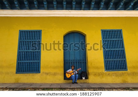 TRINIDAD, CUBA - DECEMBER 7, 2013: Old man playing the guitar in front of one of the colonial buildings. Cuban music is an attraction for the over 2 million tourists who go to Cuba each year.