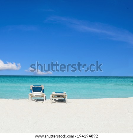 Romantic view of two sunbeds on gold sand beach