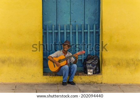 TRINIDAD, CUBA - DECEMBER 7, 2013: Msn playing the guitar in front of one of the colonial buildings. Cuban music is an attraction for the over 2 million tourists who go to Cuba each year.