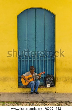 TRINIDAD, CUBA - DECEMBER 7, 2013: Man playing the guitar in front of one of the colonial buildings. Cuban music is an attraction for the over 2 million tourists who go to Cuba each year.