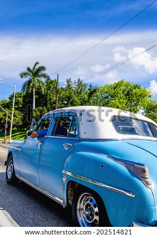 HAVANA, CUBA - DECEMBER 2, 2013: Old classic American blue car on the one of Havana streets, where old cars are relic of Cuban revolution and still attracts many tourists.