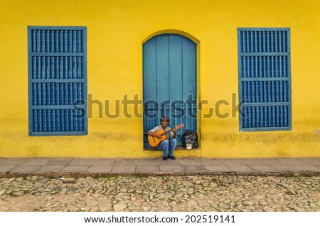 TRINIDAD, CUBA - DECEMBER 7, 2013: Man playing the guitar in front of one of the colonial buildings. Cuban music is an attraction for the over 2 million tourists who go to Cuba each year.