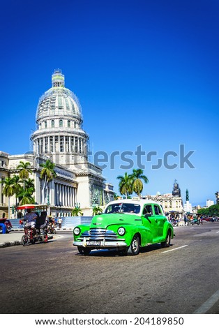 HAVANA, CUBA - DECEMBER 2, 2013: Old classic American green car rides in front of the Capitol. Before a new law issued on October 2011, cubans could only trade cars that were on the road before 1959.