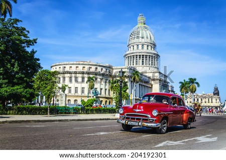 HAVANA, CUBA - DECEMBER 2, 2013: Old classic American maroon car rides in front of the Capitol. Before a new law issued on October 2011, cubans could only trade cars that were on the road before 1959.