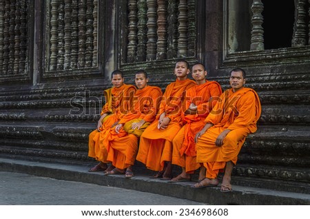 CAMBODIA, SIEM REAP ANGKOR WAT - NOVEMBER 6, 2014: Buddhist monks in reddish yellow robes in one of the famous temples of Angkor Wat, Siem Reap, Cambodia