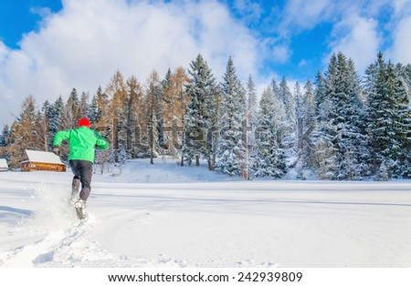 Young man in green jacket running in deep snow