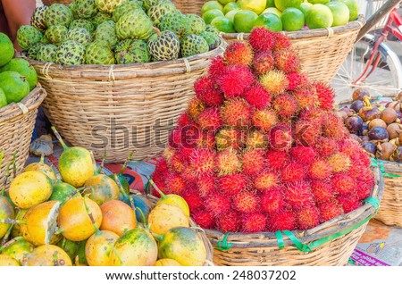 Baskets at a street market full of tropical fruit: rambutan, passion fruit, sapote, chirimoya, lime
