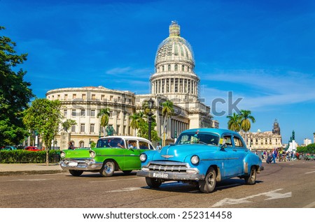 HAVANA, CUBA - DECEMBER 2, 2013: Old classic American cars rides in front of the Capitol. Before a new law issued on October 2011, cubans could only trade cars that were on the road before 1959.