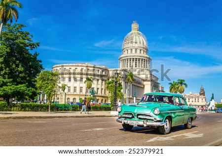 HAVANA, CUBA - DECEMBER 2, 2013: Old classic American grenn car rides in front of the Capitol. Before a new law issued on October 2011, cubans could only trade cars  that were on the road before 1959