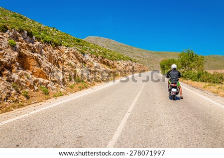 Young man driving scooter on empty asphalt road, Greek Island Kalymnos, Greece