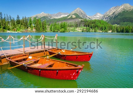 Red boats on the background of the high peaks of the Tatra Mountains and mountain lake, Strbske Pleso, High Tatras, Slovakia