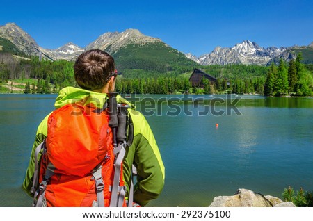 Young man admires the view of high mountains and mountain lake in National Park High Tatra, Slovakia, Europe