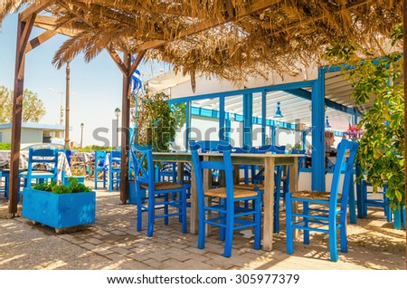 Blue wooden tables and chairs in a Greek restaurant on the beach on the seafront, Kos, Greece