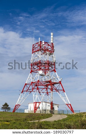Close-up of a four legged communications tower on a green grass field