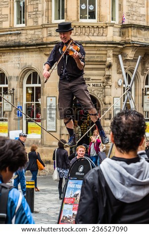 Edinburgh, Scotland - September 14, 2014: street performer balancing on a rope while playing a violin. The High Street section of the Royal Mile is a preferred stage for street performances.