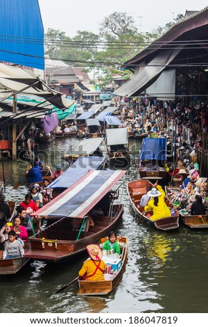 AMPHAWA, THAILAND - MARCH 29, 2014: crowd of people and wooden boats at the famous Floating Market near Bangkok. A traditional method of buying via boat became to attraction forigner touris.