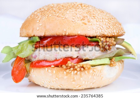 Burger with turkey, lettuce, onions, red paprika pepper on a sesame seed bun.