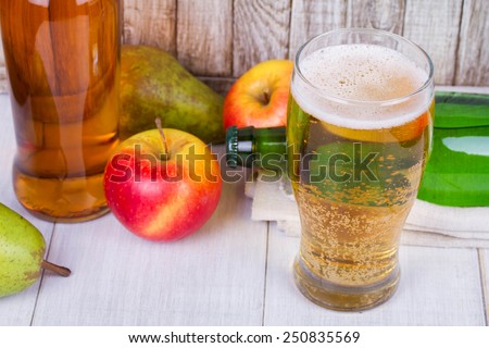 Glass and bottles of cider with fruits