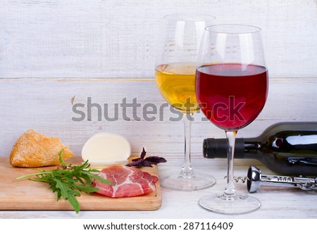 Glass and bottle of wine, cheese and prosciutto