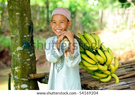 Happy Muslim boy holding bananas