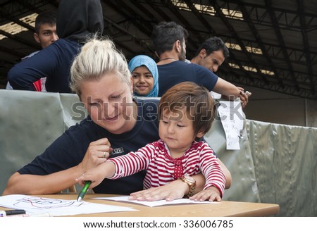 Passau, Germany - August 1, 2015: A german police officer takes care of a little refugee child in the registration area of Passau.
