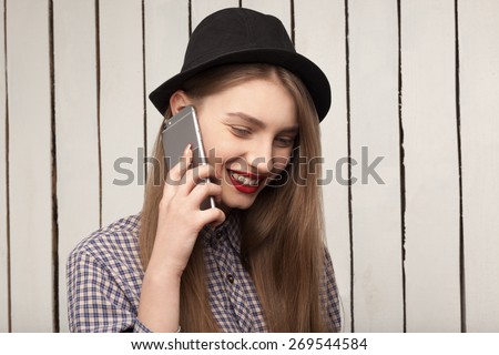 beautiful, cheerful, joyful,happy girl in shirt and hat talking on the phone, red lips