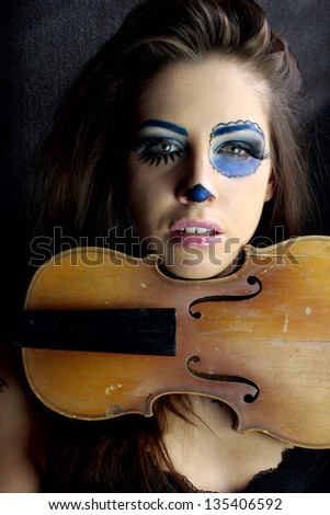 Detail view of young girl with violin and scary makeup