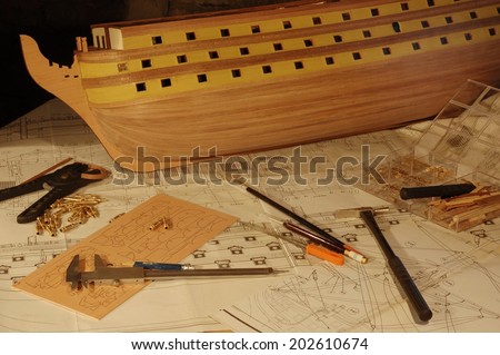 Wooden model ship with blueprints and tools