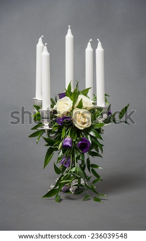 Candlestick with five white candles and roses on grey background
