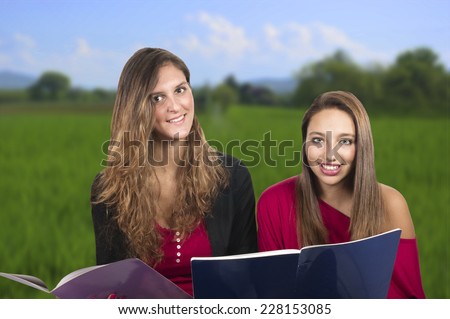 Two beautiful teenage students studying in the park